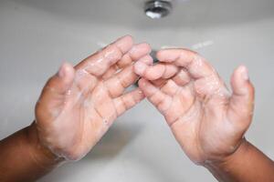 child making a cleansing gesture with soap and water on hands photo
