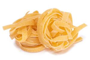 Two Classic Italian Raw Egg Fettuccine - Isolated on White Background. Dry Twisted Uncooked Pasta. Italian Culture and Cuisine. Raw Golden Macaroni Pattern - Isolation photo