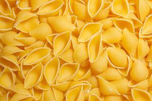 Uncooked Conchiglie Pasta. A Culinary Canvas of Conchiglie Macaroni, Creating a Lively and Textured Background for Gourmet Cooking. Dry Pasta. Raw Macaroni - Top View, Flat Lay photo