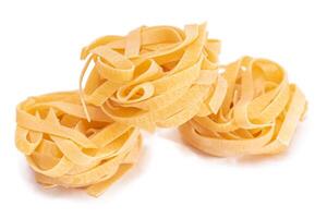 Three Classic Italian Raw Egg Fettuccine - Isolated on White Background. Dry Twisted Uncooked Pasta. Italian Culture and Cuisine. Raw Golden Macaroni Pattern - Isolation photo