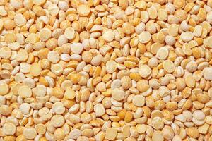 Uncooked Polished Split Peas Background. A Culinary Canvas of Dry Yellow Peas, Creating a Lively and Textured Background for Gourmet Cooking. Scattered Raw Polished Peas. Healthy Eating Ingredients photo