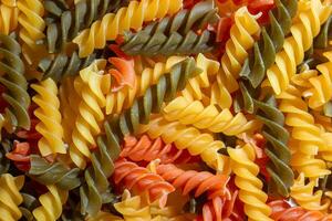 Uncooked Vibrant Colored Fusilli Pasta. A Mesmerizing Culinary Canvas of Multicolored Spirals, Creating a Lively and Textured Background for Gourmet Cooking. Colored Dry Pasta. Raw Macaroni photo