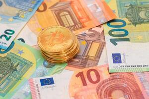 A Stack of Bitcoin Coins on the Euro Banknotes. Money Saving, Cryptocurrency, Blockchain and Anonymous Payments Concept photo