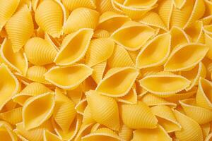Uncooked Conchiglie Pasta. A Culinary Canvas of Conchiglie Macaroni, Creating a Lively and Textured Background for Gourmet Cooking. Dry Pasta. Raw Macaroni - Top View, Flat Lay photo