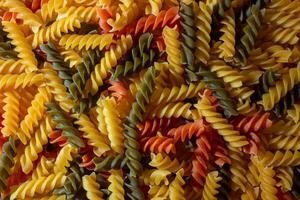 Uncooked Vibrant Colored Fusilli Pasta. A Mesmerizing Culinary Canvas of Multicolored Spirals, Creating a Lively and Textured Background for Gourmet Cooking. Colored Dry Pasta. Raw Macaroni photo