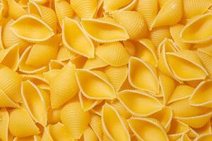 Uncooked Conchiglie Pasta. A Culinary Canvas of Conchiglie Macaroni, Creating a Lively and Textured Background for Gourmet Cooking. Dry Pasta. Raw Macaroni - Top View, Flat Lay photo