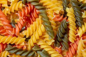 Uncooked Vibrant Colored Fusilli Pasta. A Mesmerizing Culinary Canvas of Multicolored Spirals, Creating a Lively and Textured Background for Gourmet Cooking. Colored Dry Pasta. Raw Macaroni photo