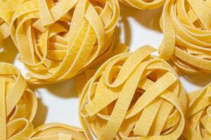 Uncooked Egg-Based Fettuccine Pasta. A Culinary Canvas of Ribbon-Shaped Macaroni, Creating a Lively and Textured Background for Gourmet Cooking. Dry Pasta. Raw Macaroni - Top View, Flat Lay photo