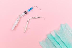 Anti Vaccine Movement and Anti Mask Concept - Broken Medical Syringe and Green Torn Medical Face Mask on the Pink Background. Pandemic and Lockdown End - Top View, Flat Lay photo