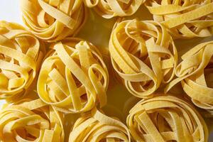 Uncooked Egg-Based Fettuccine Pasta. A Culinary Canvas of Ribbon-Shaped Macaroni, Creating a Lively and Textured Background for Gourmet Cooking. Dry Pasta. Raw Macaroni - Top View, Flat Lay photo