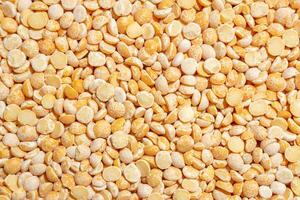 Uncooked Polished Split Peas Background. A Culinary Canvas of Dry Yellow Peas, Creating a Lively and Textured Background for Gourmet Cooking. Scattered Raw Polished Peas. Healthy Eating Ingredients photo