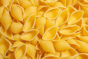 Uncooked Conchiglie Pasta. A Culinary Canvas of Conchiglie Macaroni, Creating a Lively and Textured Background for Gourmet Cooking. Dry Pasta. Raw Macaroni - Top View, Flat Lay photo