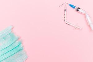 Anti Vaccine Movement and Anti Mask Concept - Broken Medical Syringe and Green Torn Medical Face Mask on the Pink Background. Pandemic and Lockdown End - Top View, Flat Lay photo