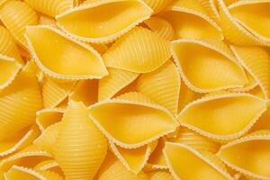 Uncooked Conchiglie Pasta. A Culinary Canvas of Conchiglie Macaroni, Creating a Lively and Textured Background for Gourmet Cooking. Dry Pasta. Raw Macaroni - Top View, Flat Lay photo