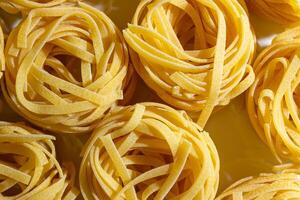 Uncooked Egg-Based Fettuccine Pasta. A Culinary Canvas of Ribbon-Shaped Macaroni, Creating a Lively and Textured Background for Gourmet Cooking. Dry Pasta. Raw Macaroni - Top View, Flat Lay photo