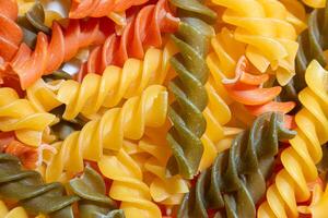 Uncooked Vibrant Colored Fusilli Pasta. A Mesmerizing Culinary Canvas of Multicolored Spirals, Creating a Lively and Textured Background for Gourmet Cooking. Colored Dry Pasta. Raw Macaroni photo