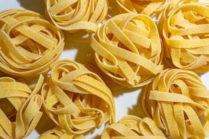 Uncooked Egg-Based Fettuccine Pasta. A Culinary Canvas of Ribbon-Shaped Macaroni, Creating a Lively and Textured Background for Gourmet Cooking. Dry Pasta. Raw Macaroni - Top View, Flat Lay photo