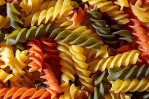 Uncooked Vibrant Colored Fusilli Pasta. A Mesmerizing Culinary Canvas of Multicolored Spirals, Creating a Lively and Textured Background for Gourmet Cooking. Colored Dry Pasta. Raw Macaroni photo