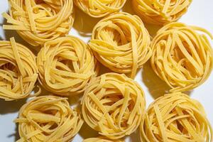 Uncooked Egg-Based Fettuccine Pasta. A Culinary Canvas of Ribbon-Shaped Macaroni, Creating a Lively and Textured Background for Gourmet Cooking. Dry Pasta. Raw Macaroni - Top View, Flat Lay photo