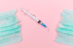Anti Vaccine Movement and Anti Mask Concept - Broken Medical Syringe and Green Torn Medical Face Mask on the Pink Background. Pandemic and Lockdown End - Top View, Flat Lay photo