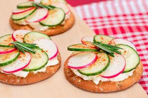 Light Breakfast or Diet Eating - Crispy Cracker Sandwich with Cream Cheese, Fresh Cucumber and Radish on Wooden Cooking Board on Magenta Background photo