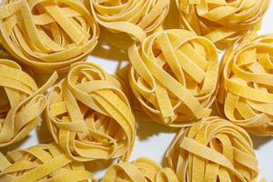 Uncooked Egg-Based Fettuccine Pasta. A Culinary Canvas of Ribbon-Shaped Macaroni, Creating a Lively and Textured Background for Gourmet Cooking. Dry Pasta. Raw Macaroni - Top View, Flat Lay photo
