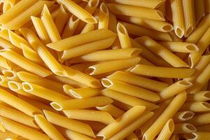 Uncooked Penne Rigate Pasta. A Culinary Canvas of Penne Macaroni, Creating a Lively and Textured Background for Gourmet Cooking. Dry Pasta. Raw Macaroni - Top View, Flat Lay photo