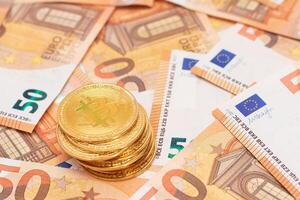 A Stack of Bitcoin Coins on the 50 Euro Banknotes. Euro Currency and Crypto Currency. Orange Paper Money. A Lot of Fifty-Euro Bills. Finances, Cash, Anonymous Payments and Money Saving Concept photo