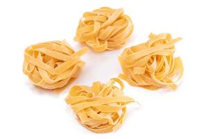Four Classic Italian Raw Egg Fettuccine - Isolated on White Background. Dry Twisted Uncooked Pasta. Italian Culture and Cuisine. Raw Golden Macaroni Pattern - Isolation photo