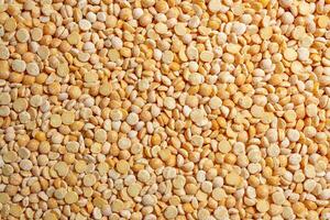 Uncooked Polished Split Peas Background. A Culinary Canvas of Dry Yellow Peas, Creating a Lively and Textured Background for Gourmet Cooking. Scattered Raw Polished Peas. Healthy Eating Ingredients photo