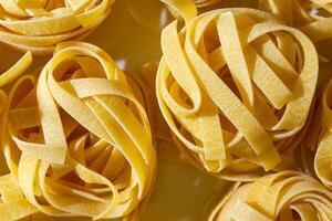 Uncooked Egg-Based Fettuccine Pasta. A Culinary Canvas of Ribbon-Shaped Macaroni, Creating a Lively and Textured Background for Gourmet Cooking. Dry Pasta. Raw Macaroni - Top View, Flat Lay photo