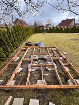 Framework of a wooden deck under construction in a backyard with trees and greenery in the background. photo