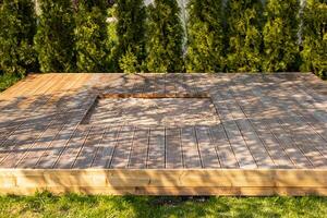 Wooden deck with central sandpit in a backyard setting, surrounded by trees and natural surroundings photo