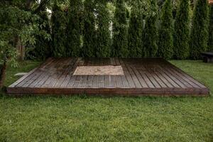 Wooden deck with central sandpit in a backyard setting, surrounded by trees and natural surroundings photo