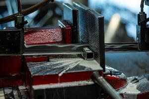 Detailed view of a red metalworking machine in a factory, cutting a metal piece with coolant fluid. Focus on precision and technical aspects of the process. photo
