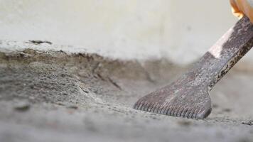 A closeup of a diligent worker scraping a concrete surface with a specialized tool video
