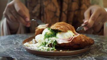 Woman Enjoying Delicious Breakfast Croissant with Eggs and Ham on a Plate video