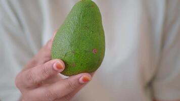 A Fresh Green Avocado Being Held by a Hand and Bathed in Beautiful Natural Light video