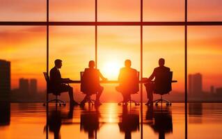 group of colleagues working together in meeting room at sunset, discussing strategies and ideas. silhouettes create dramatic atmosphere photo