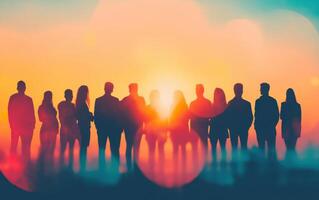 group of colleagues standing together against vibrant sunset, showcasing teamwork and collaboration. silhouettes create striking visual against colorful backdrop photo