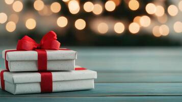 Festive Christmas gifts stacked with red ribbons on wooden table, creating joyful atmosphere. blurred lights in background enhance holiday spirit photo