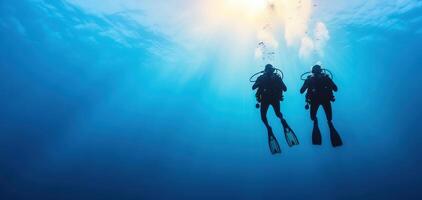 Diving adventurers explore deep blue waters, surrounded by vibrant marine life and sunlight filtering through surface, creating serene underwater experience photo