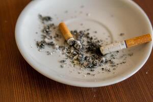 closeup of smoking ashtray with ashes and broken cigarette photo
