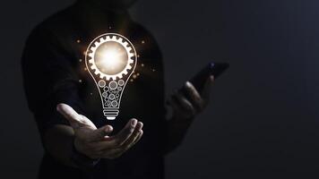Businessman using smartphone and showing new idea with light bulb on hand for innovation and inspiration. photo
