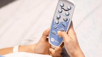patient presses the up and down button on the remote control to raise and lower the head of the bed in the clinic to find a comfortable resting position, recovery and care concept, video