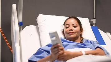 Young patient in blue gown adjusting pillow height on functional electric bed with remote control, raising and lowering it to find comfortable resting position, woman smiling and enjoying, video