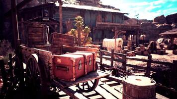 Old wooden cart loaded with boxes near rustic structures under blue sky video