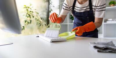 Attentive Cleaner Using Dustpan on Office Keyboard photo