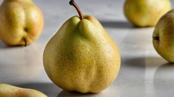 A close-up of a ripe pear on a marble surface, surrounded by more pears. photo