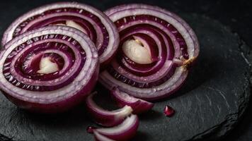 Sliced red onions arranged on a dark slate surface, showcasing their vibrant colors and texture. photo